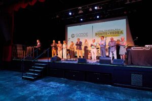 A group of people standing on stage in front of a screen.